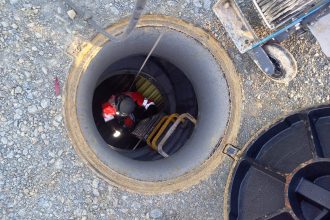 Technicien sécurisé en descente dans un regard